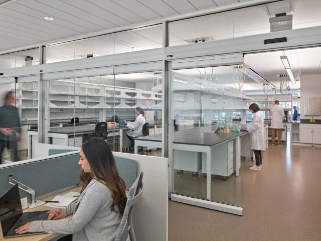 View of one workstation with woman working next to a lab space